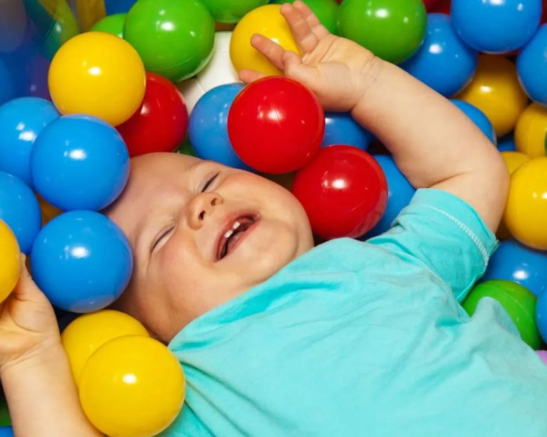 Bebé jugando en piscina de pelotas de colores.